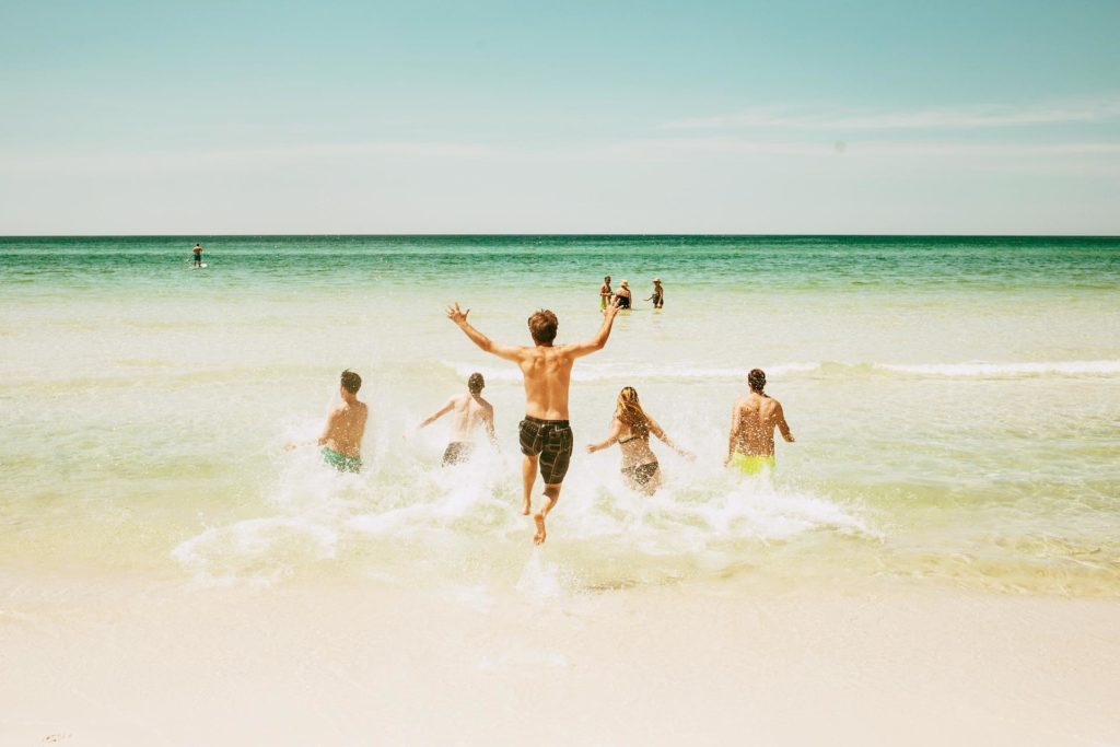 Gruppenreisen: Gruppe von Freunden rennt ins Meer
